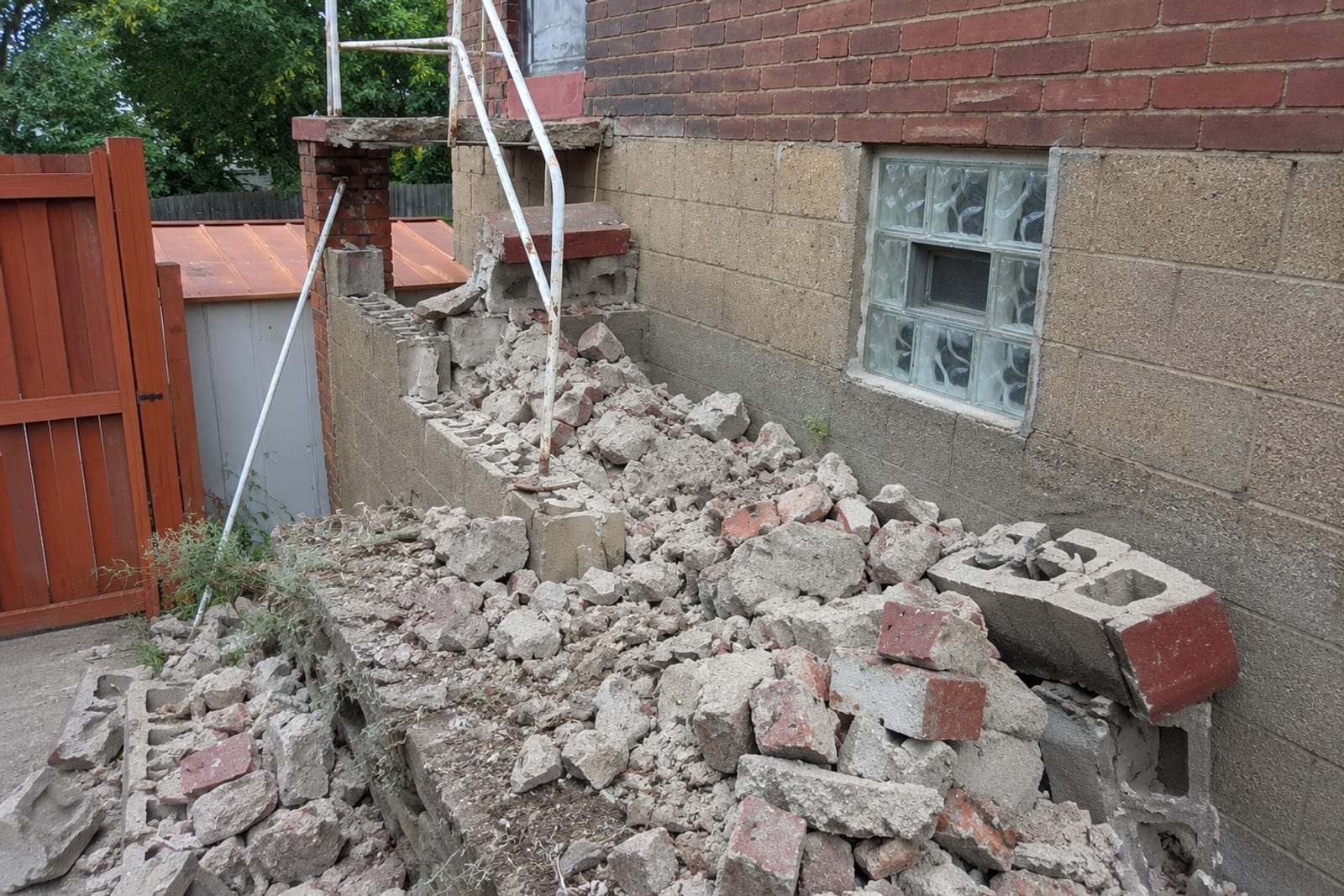 Broken-out concrete steps and block wall stacked for removal at a Pittsburgh property