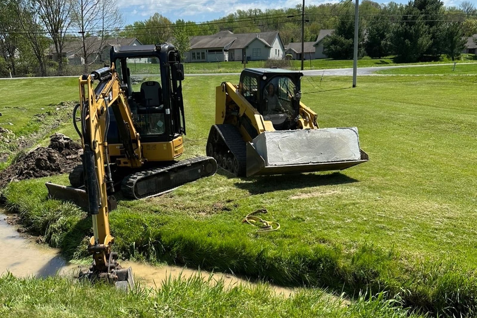 Excavator and track loader working an open drainage channel on a Pittsburgh site