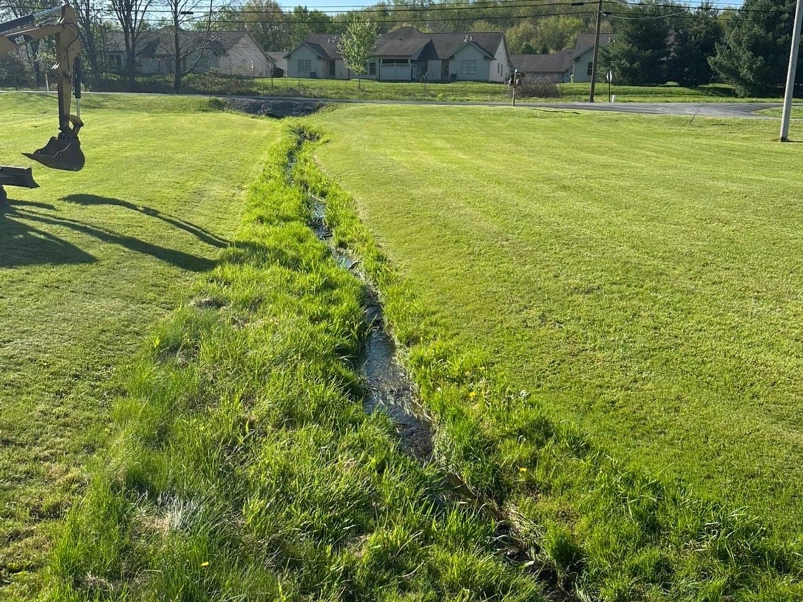 Drainage swale cut across a lawn during French drain installation in Pittsburgh