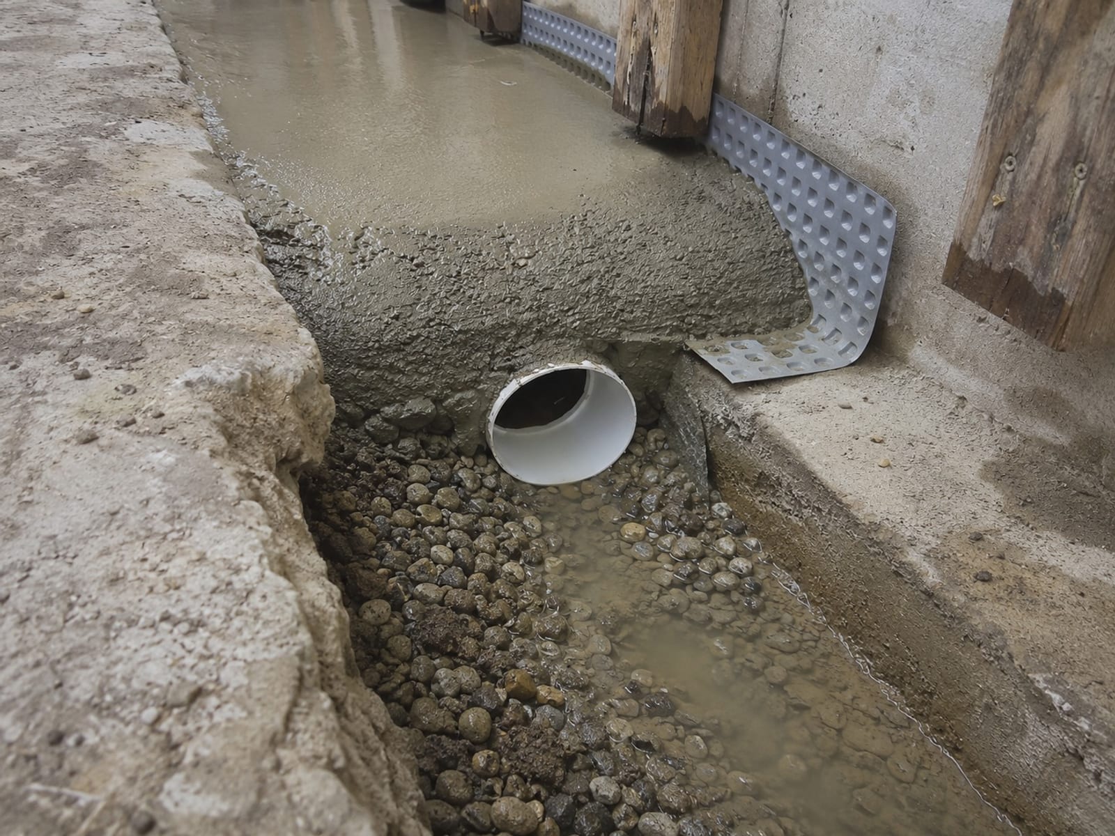 Perforated drain pipe set in washed stone below slab level in a Pittsburgh basement