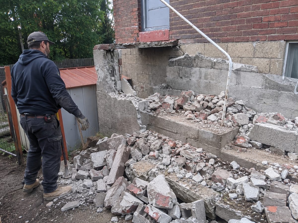 Demolition crew member breaking out a concrete stair and block wall in Pittsburgh