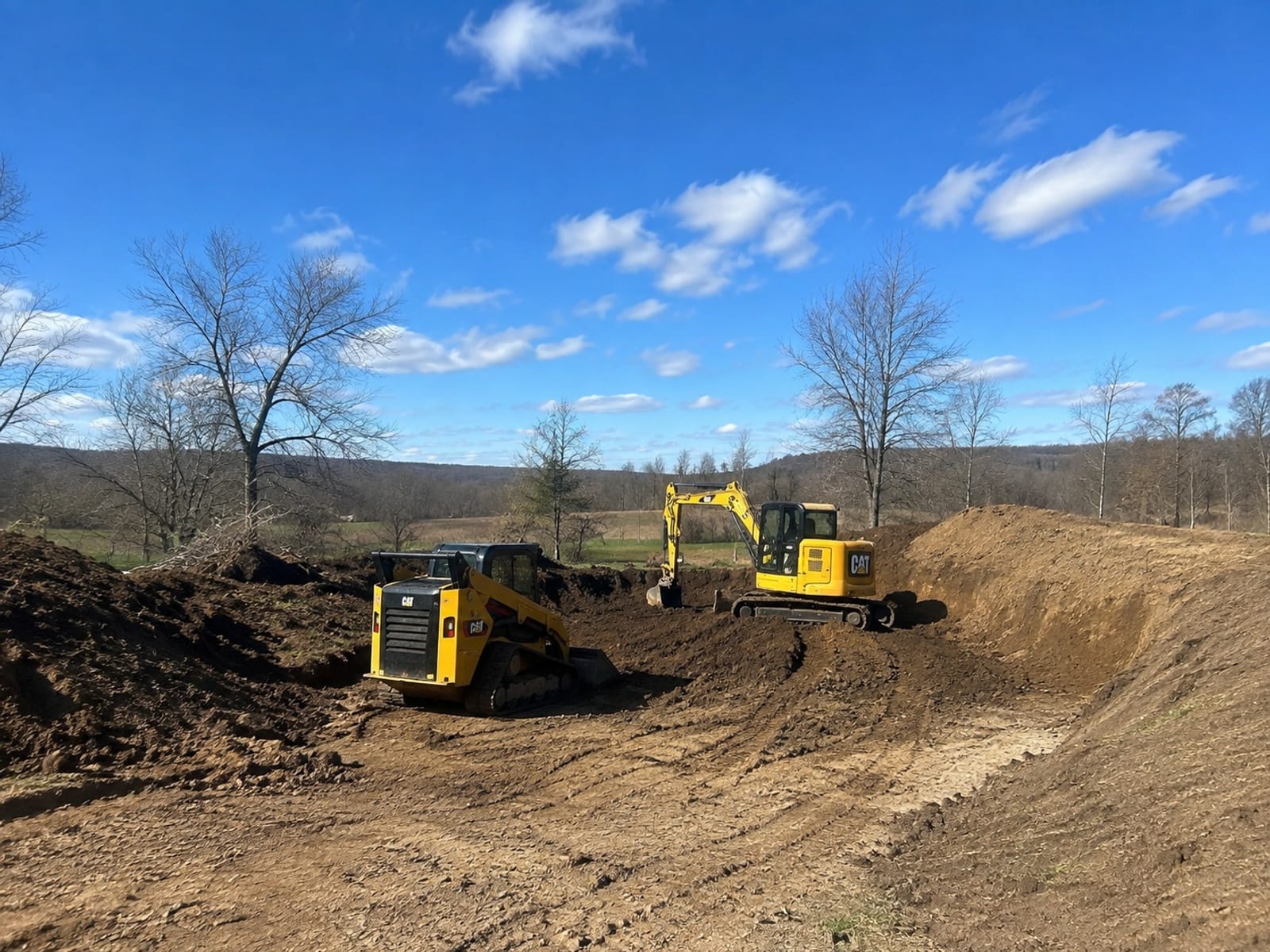 Excavator and track loader working a bulk earthmoving cut on a Pittsburgh site