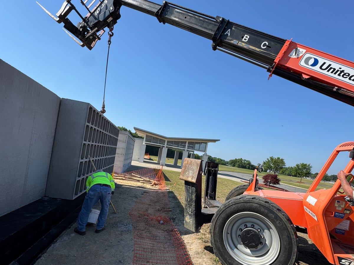 Telehandler setting a precast concrete open-grid wall unit into position