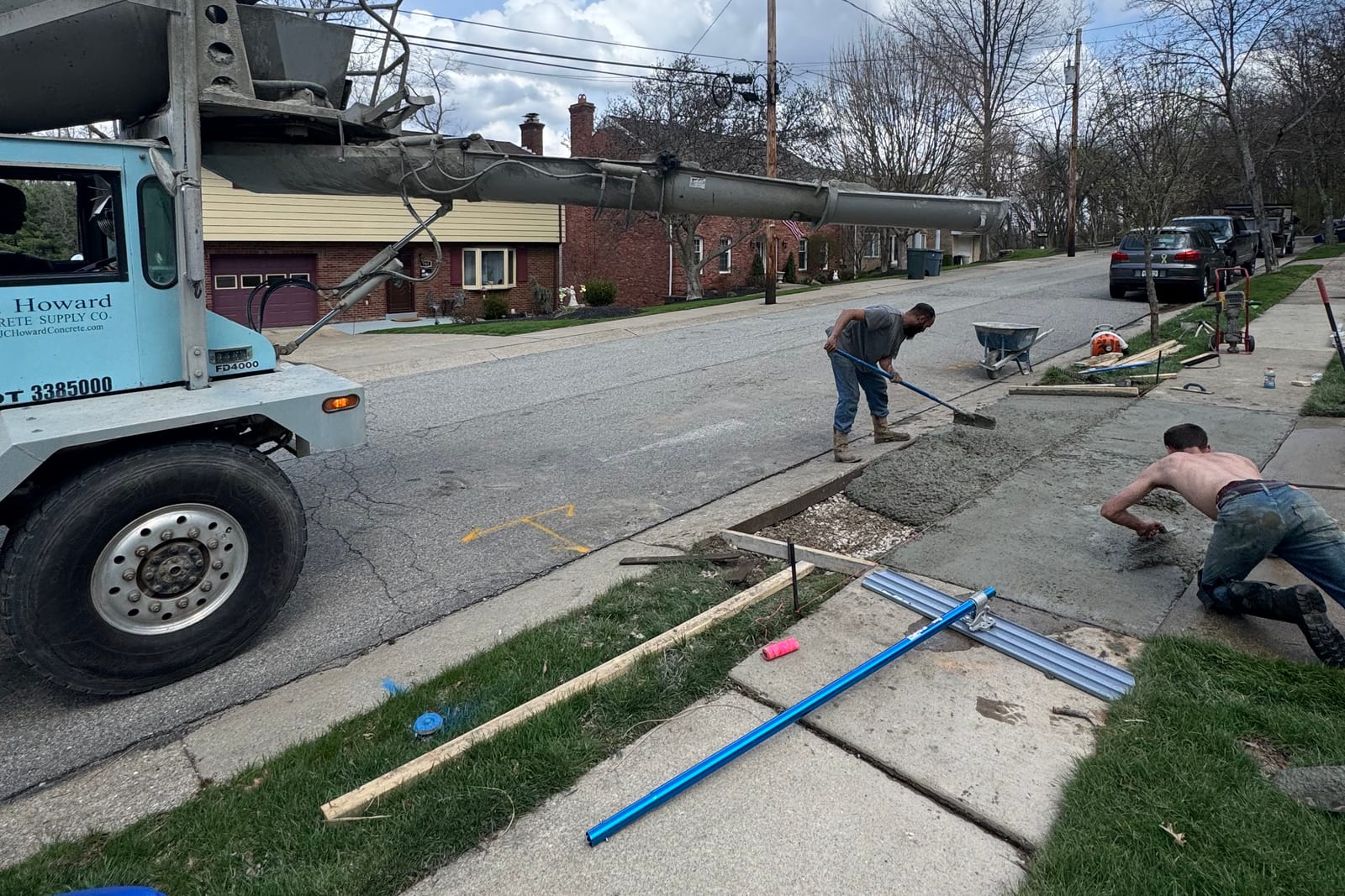 Sidewalk repair contractors placing and finishing concrete from a mixer truck in Pittsburgh